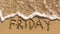 Inscription FRIDAY on a gentle beach sand with the soft wave