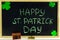 The inscription with green chalk on a chalkboard: Happy St. Patrick\'s Day. Clover leaves. Chest with coins.