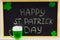 The inscription with green chalk on a chalkboard: Happy St. Patrick\'s Day. Clover leaves. A mug with green beer.