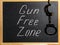 Inscription Gun Free Zone in chalk and handcuffs on a school blackboard