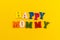 The inscription `Happy Mommy` in colorful letters on a yellow background