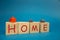 the inscription of the house on wooden cubes and different tiny houses. blue background