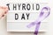 Inscription international thyroid day, violet ribbon and womans hand holding a letter on white background