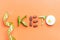 Inscription keto composed of vegetables and measuring tape on orange background