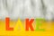 Inscription lake from multicolored bright wooden letters lie on a bright yellow background copy space. holiday vacation concept