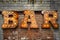 Inscription from large metal letters decorated with glowing light bulbs on the brick wall