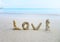 The inscription love laid out on the sand from corals, against the background of the sea, Thailand