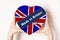 Inscription Made in Britain, the flag of Britain. Female hands holding a heart shaped box. White background. Place for text