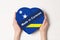 Inscription Made in Curacao the flag of Curacao. Female hands holding a heart shaped box. White background