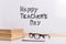 The inscription marker on a white board, Happy Teacher's Day. A table with books and glasses