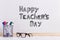 The inscription marker on a white board, Happy Teacher`s Day. A table with glasses and attributes for writing