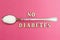 The inscription `no diabetes`, a spoon with sugar on a pink background, concept