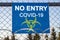 The inscription `NO ENTRY COVID-19` on a blue plate