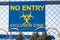 The inscription `NO ENTRY exclusion zone` and biohazard caution sign in yellow on a blue plate