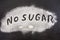 The inscription` no sugar`. Sugar on a black background. Disease Warning.