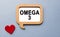 The inscription OMEGA 3 on a wooden template, against the background of scattered a red heart. Medical concept