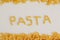 Inscription pasta on white background and spiral pasta.Top view. Copy, empty space for text