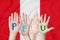Inscription Peru on the children`s hands against the background of a waving flag of the Peru