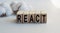 The inscription REACT on wooden cubes isolated on a light background. Concept word forming on wooden cube. Business, economics and