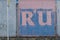 The inscription RU on a pink and blue metal wavy fence