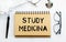 Inscription - STUDY MEDICINA. Written in a notepad to remind you of what\\\'s important. Top view of the table along with a