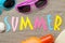 Inscription summer from paper of multi-colored letters and seashells and summer accessories on the sea sand. Summer. relaxation. v