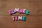 Inscription summertime by multicoloured wooden letters on wooden background. Concept happy summertime