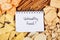 Inscription unhealthy food in notebook and heap of crisps and cookies, concept of restriction eating salted food