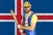 An insecure clown holds a bat in his hands against the background of the flag of Iceland