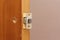 Inserting door latch in end hole close-up. Fitting door lock in panel. Markup for doorknob installing