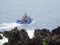 Inshore fishing vessel sailing close to rocks