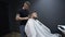 Inside barbershop salon. Male specialist fastens button on client\'s cape. Thin barber and fat chubby bearded visitor