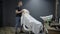 Inside barbershop salon. Thin barber throws towel over client\'s face. Male specialist wipes hair on visitor\'s head