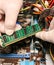 Inside details of the old personal computer. Cooler, motherboard, wires and video card in the dust. Man is holding cables in his