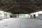 Inside of large empty military hangar with destroyed inner walls and missing windows at abandoned military complex