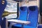 Inside of modern express train. Nobody in blue chairs at window. Comfortable chairs and table in foreground, nature outside window