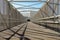 Inside of a modern overhead pedestrian bridge over an expressway on a sunny day. Diminishing perspective and shadows from fencing