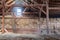 Inside Old Dirty Barn with Hay Bales Dark Wood Beams and Wooden Ladder Streaming Light from Window