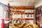 Inside of a tool shed with coiled rope in foreground and a variety of rustic tools hanging on a rough plaster wall at back -