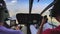 Inside view of a helicopter in flight with pilot and man flying a helicopter on a sunny day.
