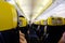 Inside view of Ryanair flight. Cabine view of the plane with flagship yellow and blue seats. Passengers seated waiting