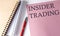 INSIDER TRADING word on the pink paper with office tools on white background