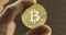 Inspecting Physical bitcoin held in hands closeup