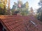 Inspection of the red tiled roof of a single-family house, inspection of the condition of the tiles on one roof side.