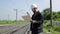 Inspector of railway traffic talking on walkie-talkie. Railway worker in white helmet holding blueprints plan