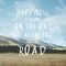 Inspirational motivational quote `Happiness is found on the way not at the end of the road.` with mountain view background.