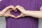 Inspire inclusion. Woman holding her hands in the shape of a heart and holding them in front of her, dressed purple