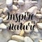 Inspire by nature. Brush hand-drawn motivational lettering. Black letters against stone background with ice. Vector