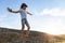 inspired boy in T-shirt, denim hat, spread his arms looking at stunning sunset