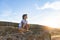 inspired boy in T-shirt, denim hat, squatting looking at stunning sunset